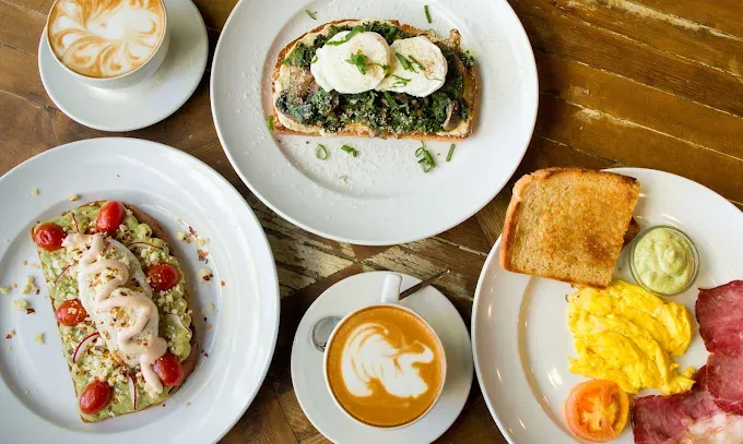 A breakfast flatlay at Meraki Coffee House with open sandwiches, eggs and coffee